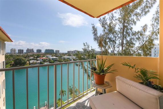 Balcony view overlooking a body of water with buildings in the distance.