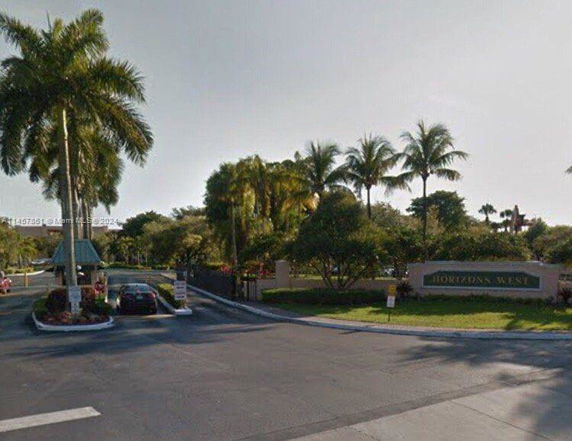 Outdoor parking area with palm trees and a sign for Horizons West.