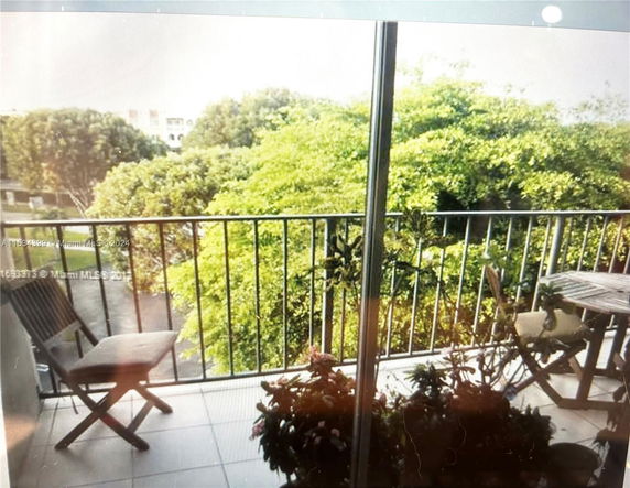 View from a balcony overlooking trees and buildings in the distance.