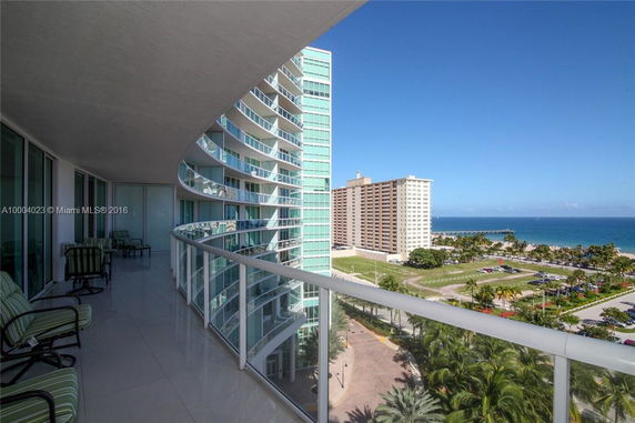 View of a high-rise building with curved balconies, overlooking a beach and ocean.