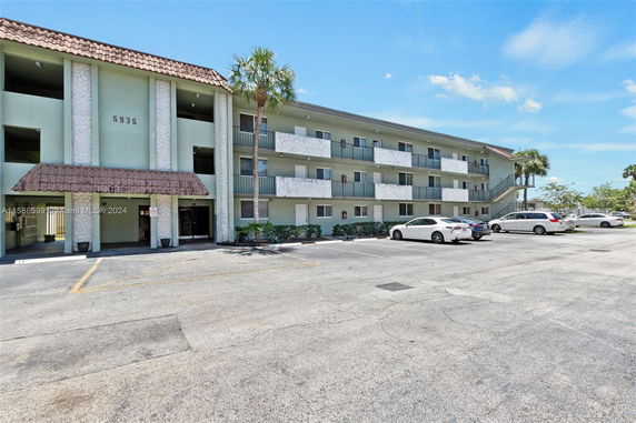 Front view of a multi-story apartment building with a parking area.
