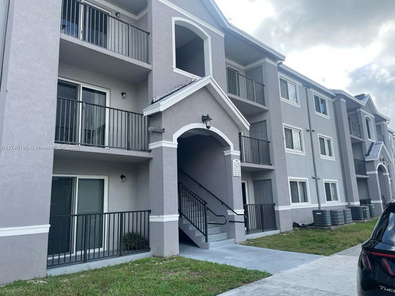 Front view of a multi-story residential building with balconies and staircases.