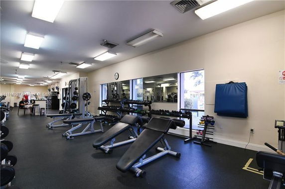 Indoor gym area with exercise equipment and weights.