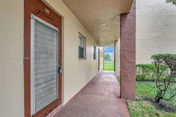 Corridor view of a building entrance with a door labeled 111 and a pathway leading outside.