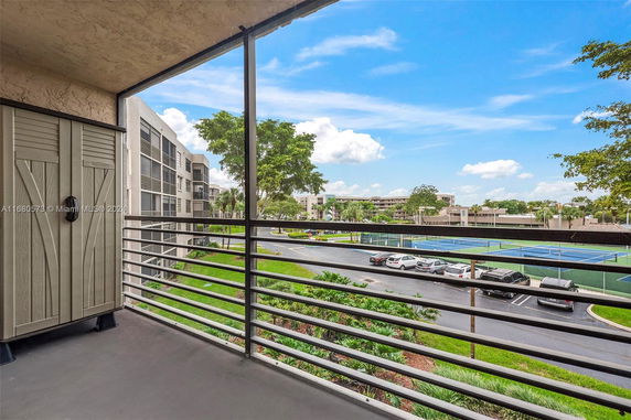 View from a balcony overlooking parking and tennis courts.