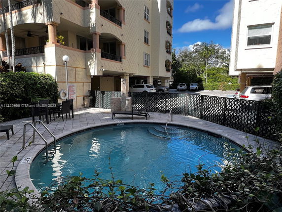 Outdoor pool area adjacent to a multi-story apartment building with balconies.