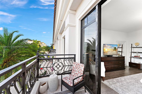 View from a balcony showing the exterior of a building with decorative railings and palm trees in the surroundings.
