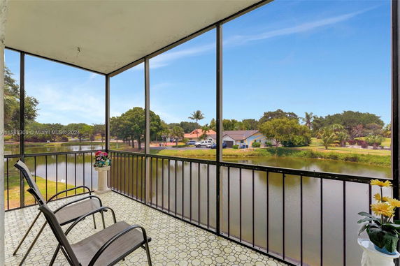 Panoramic view from a screened balcony overlooking a pond and houses.