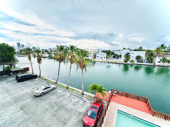 View of a canal with residential buildings and parked cars.