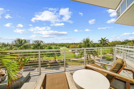 Wide angle view from a balcony overlooking lush greenery and distant skyscrapers.