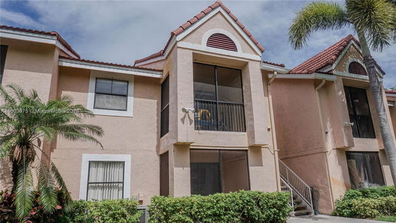 Front view of a multi-story residential building with red-tiled roof and balconies.
