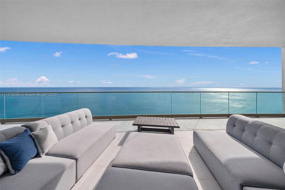 Balcony with modern seating overlooking the ocean, glass railing providing expansive sea view.