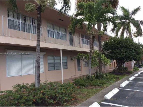 Front view of a two-story building with balconies and shutters.