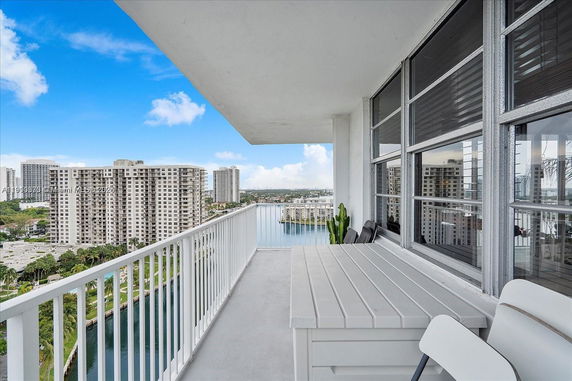 High-rise balcony with a view of distant buildings and a waterway.