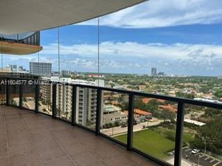 Panoramic view from a balcony overlooking a cityscape with buildings and greenery.