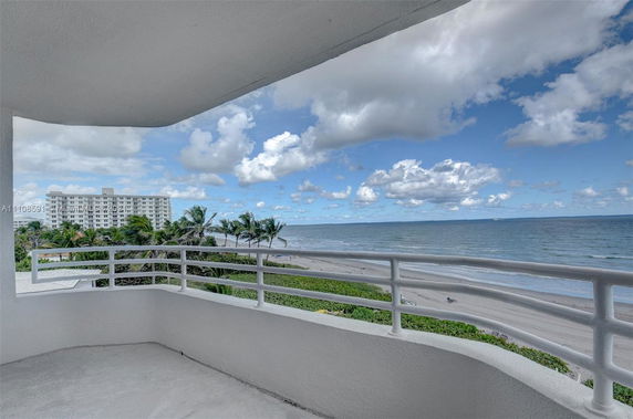 Balcony view overlooking the ocean and a distant building.