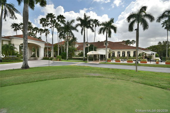 Front view of a luxury building with large windows and entrance canopy surrounded by palm trees.
