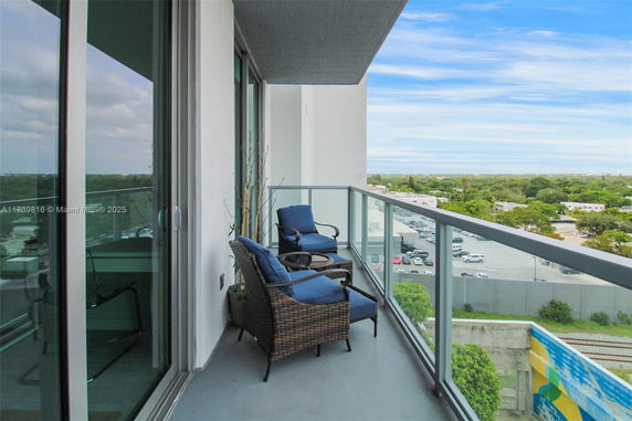 Balcony view looking over a parking area and greenery in the distance.