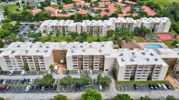 Aerial view of multiple apartment buildings with white roofs and surrounded by greenery.