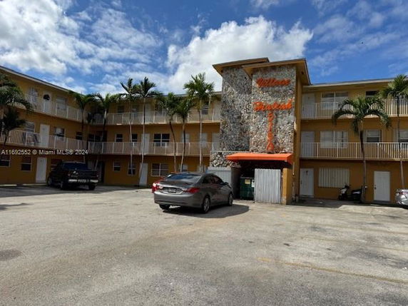Exterior view of a three-story apartment building with a parking lot in front.