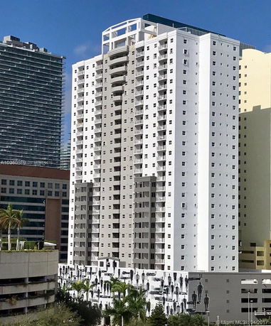 Front view of a tall, modern residential building with multiple balconies.