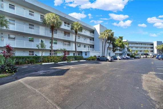 Front view of a multi-story residential building with balconies and parking area.