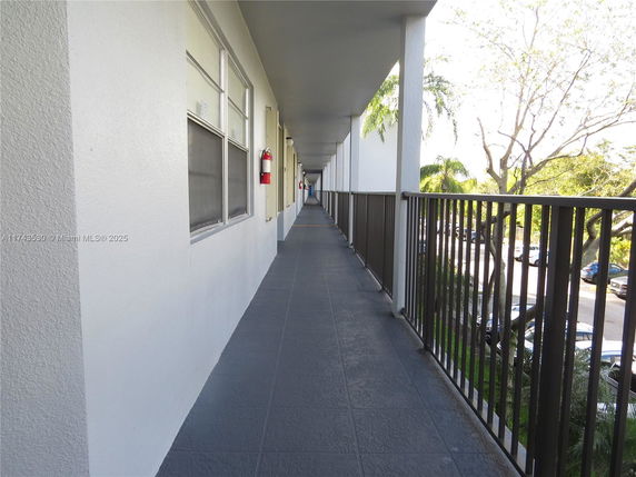 Exterior walkway of a multi-story building with metal railing and windows.