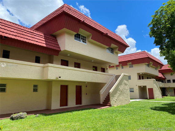 Front view of a multi-story residential building with red gabled roofs.