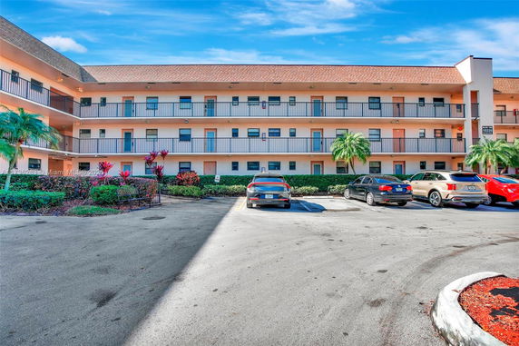 Outdoor parking area in front of a multi-story building with balconies.