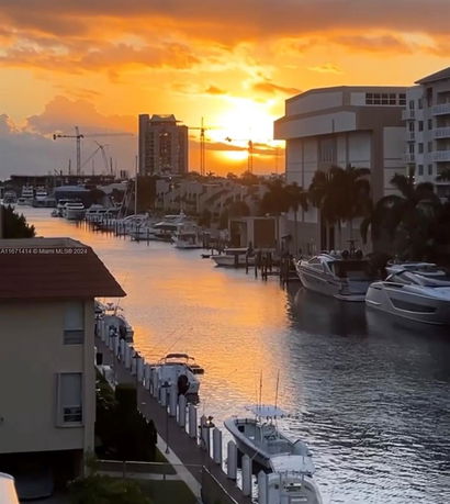 Panoramic view of a waterfront area with boats and buildings at sunset.