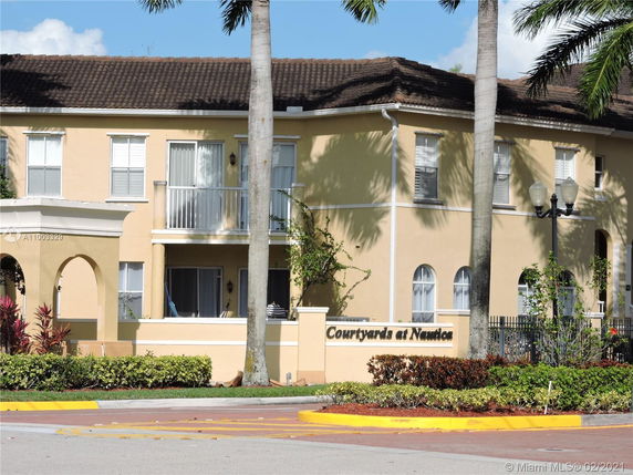 Front view of a two-story residential building with balconies and arched entryway.