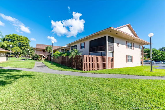 Front view of a two-story residential building with a fenced area and covered patios.