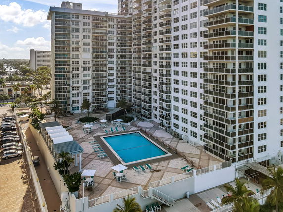 Outdoor swimming pool area surrounded by a multi-story residential building.