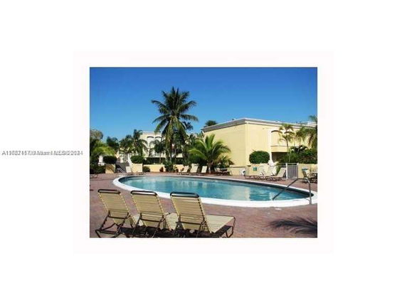 Outdoor swimming pool with lounge chairs and surrounding tropical landscape.