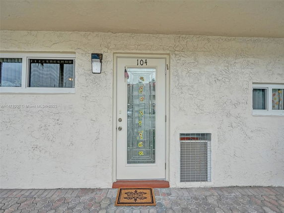 Front view of an entrance door with white textured walls and a welcome mat.