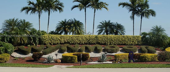 Outdoor view with landscaped hedges and palm trees.