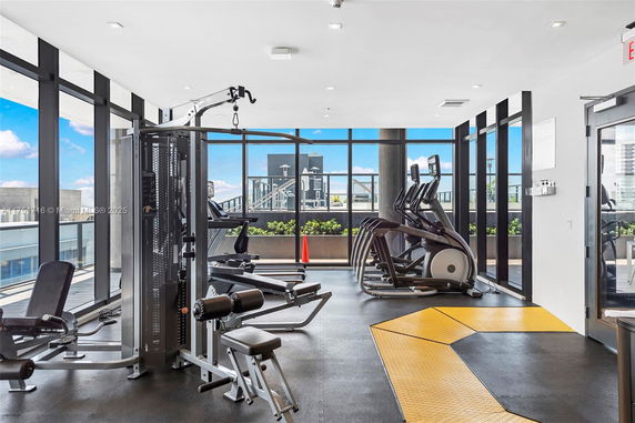 Indoor gym area with exercise equipment and large windows.