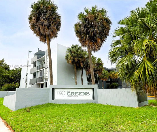 Front view of a multi-story condominium building with palm trees.