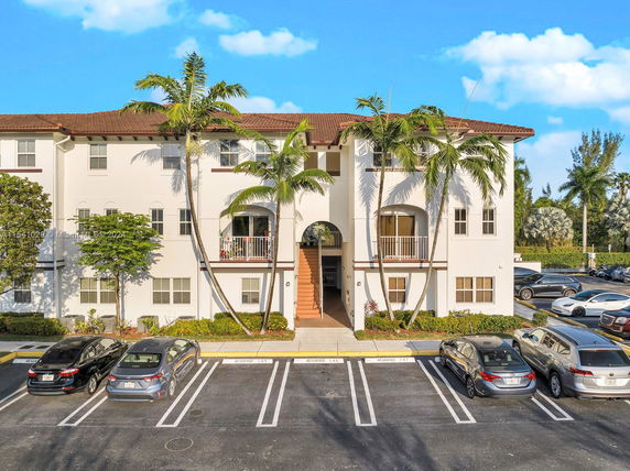 Front view of a multi-story building with arched balconies and a central staircase.
