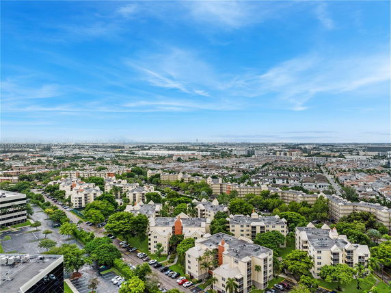 Wide angle view of residential buildings and surrounding landscape under a clear blue sky.