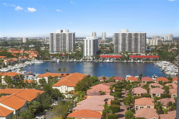 Aerial view of waterfront buildings with boats and residential areas in the foreground.