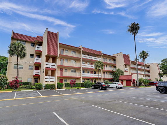 Front view of a multi-story residential building with balconies and a parking area.