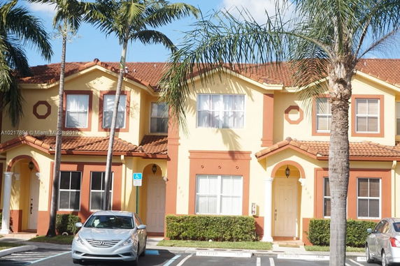 Front view of a two-story house with tile roof and arched entry.