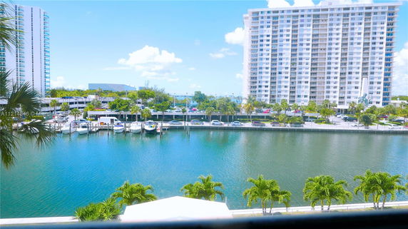 View of high-rise buildings across a waterway with boats docked along the shoreline.