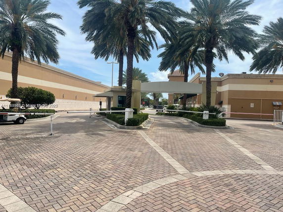 Entrance area with palm trees and gated access to buildings.