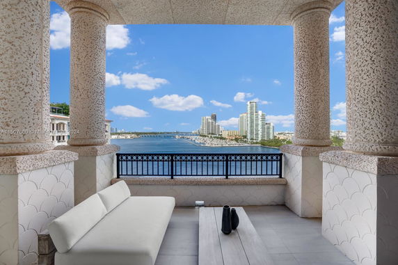 Panoramic view of a city skyline and waterway from a balcony with stone columns.