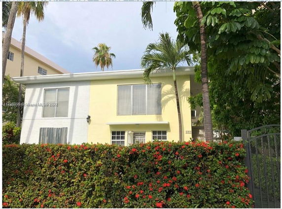 Front view of a two-story house with palm trees in the foreground.