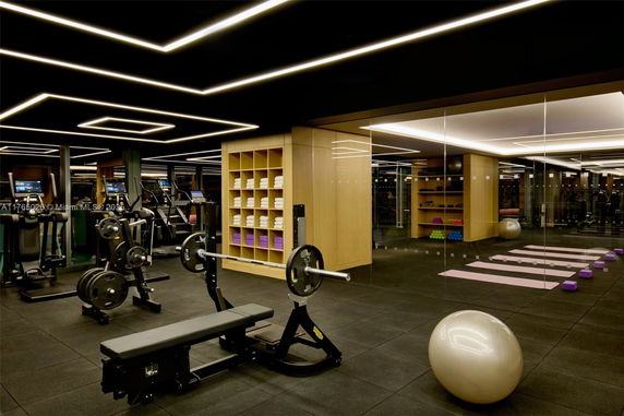 Interior view of a modern gym with exercise equipment and yoga mats.