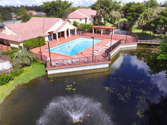 Outdoor swimming pool area with surrounding patio and nearby pond.