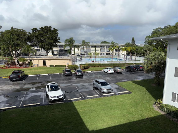 View of multi-story buildings with a parking area and swimming pool.